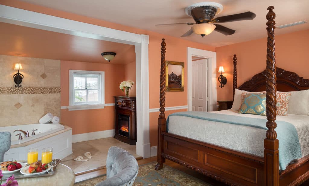 peach room with tub and four poster bed