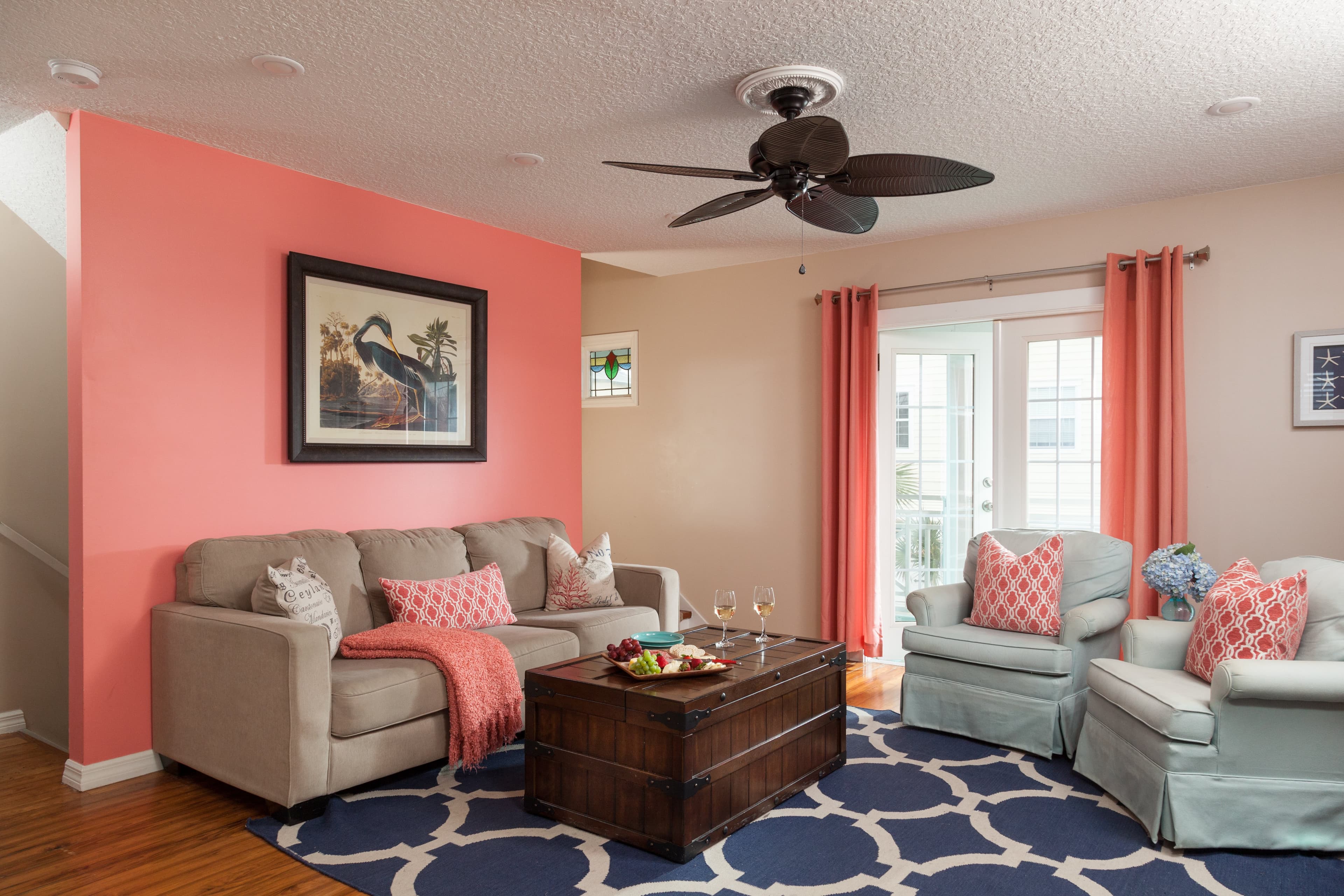 coral room with sofa chairs and ceiling fan