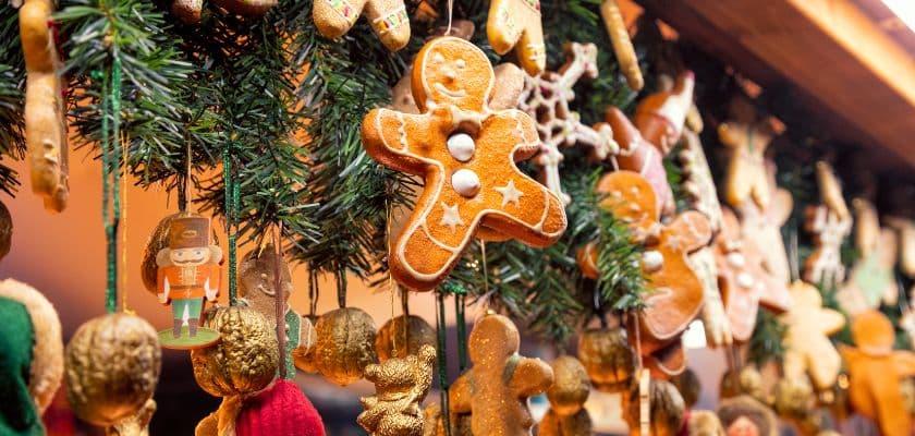 A festive display of gingerbread cookies and decorative ornaments hanging on greenery.