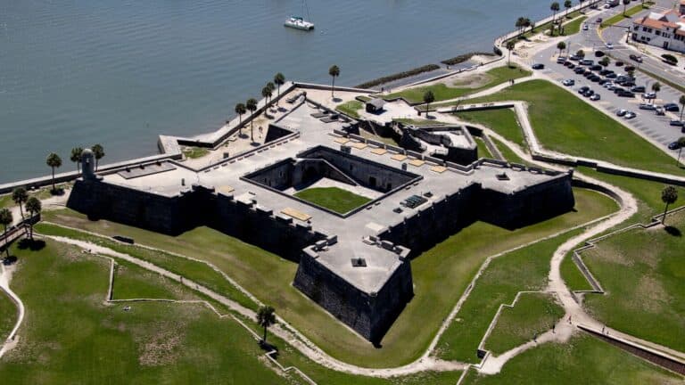 Aerial view of a historic fort surrounded by green lawns and a body of water.