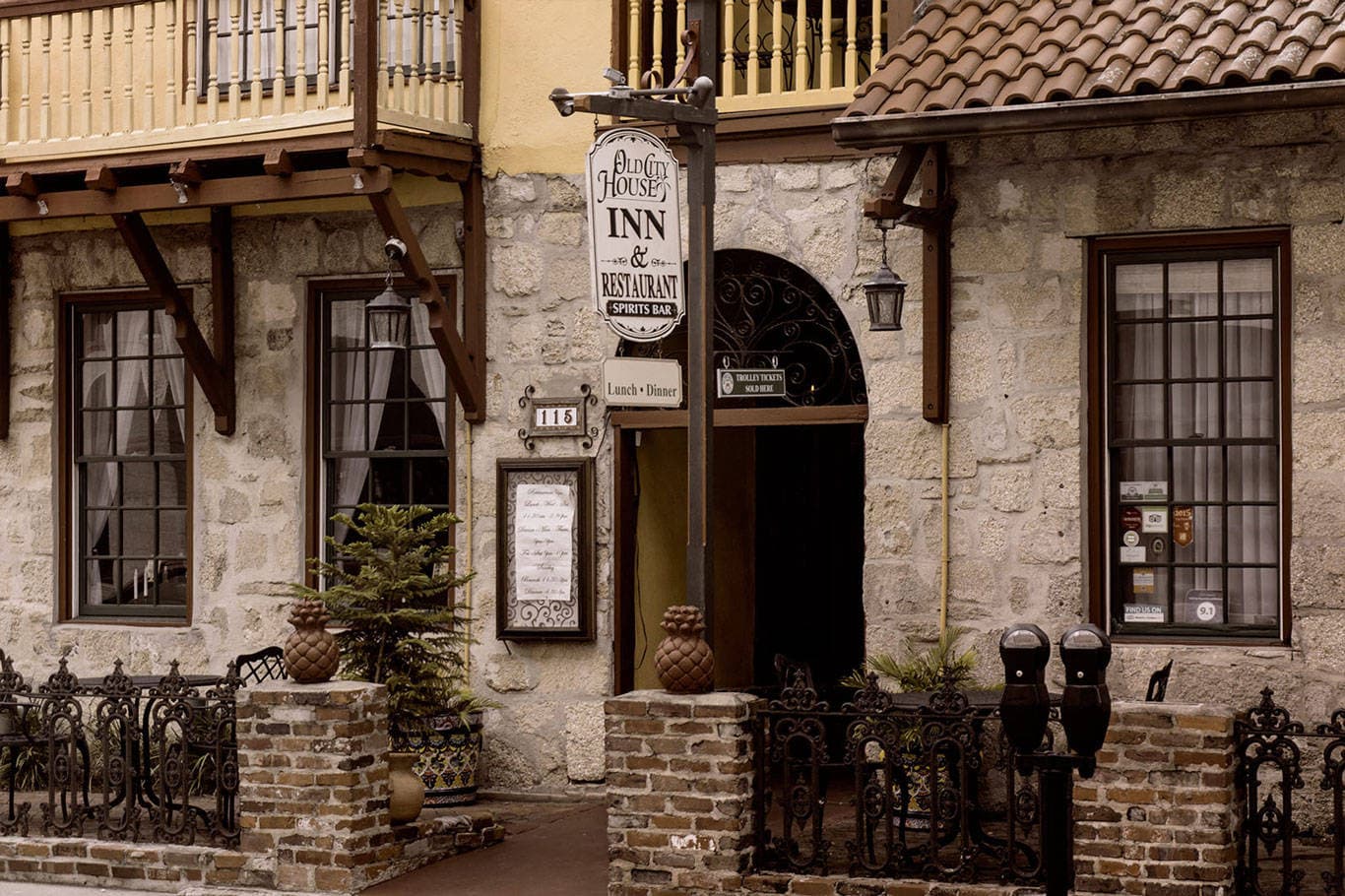 A charming stone building with a red tile roof and ornate ironwork features a prominent "Old City House Inn & Restaurant" sign.