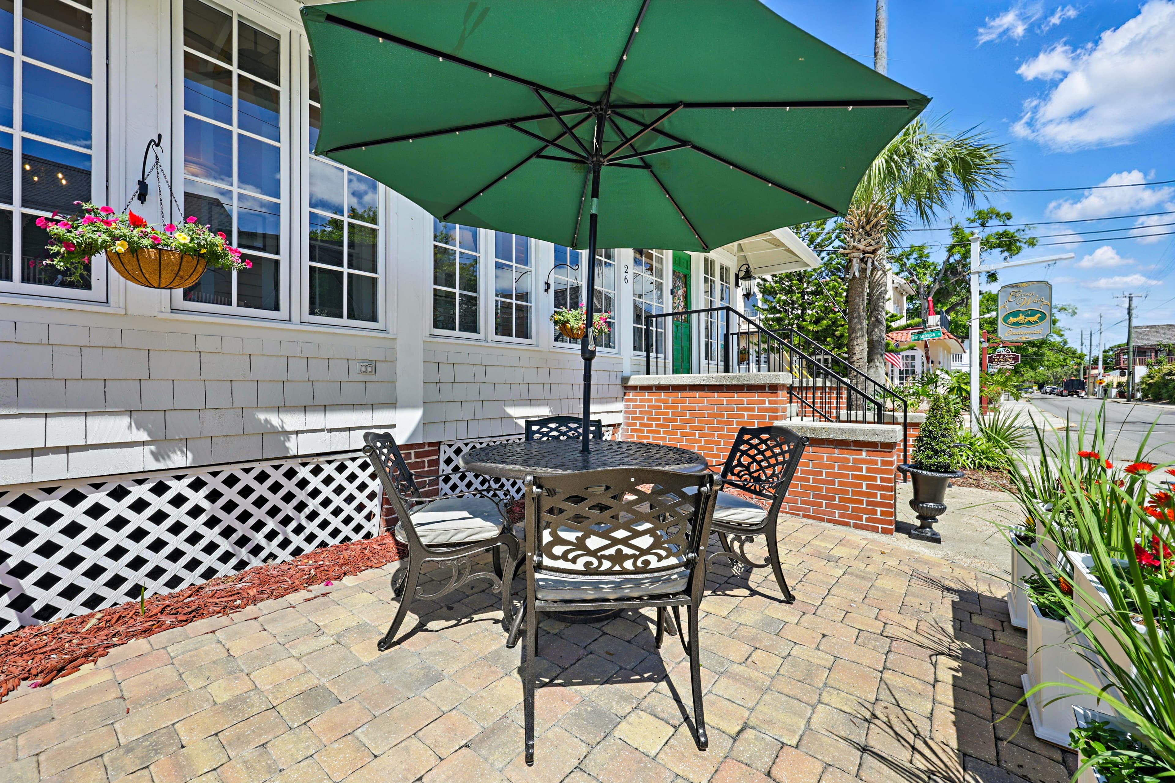 Outside view of Carriage Way Centennial building with windows all across the front, umbrella table and chairs sitting on a paver patio.