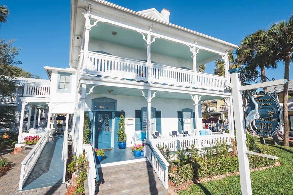 A close-up view of a two-story white building with blue trim and balconies.