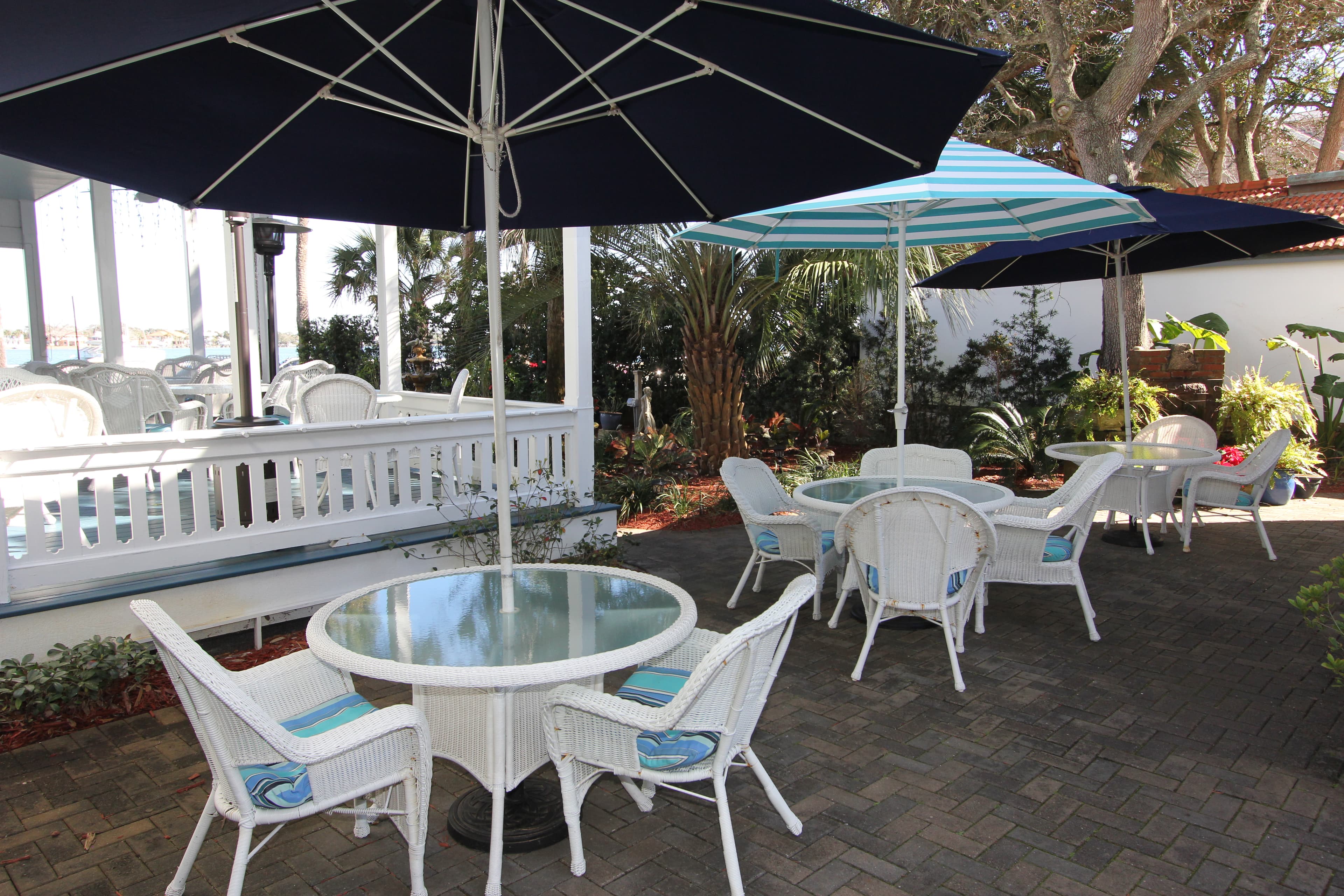 Umbrella tables in a courtyard below a wrap-around porch.