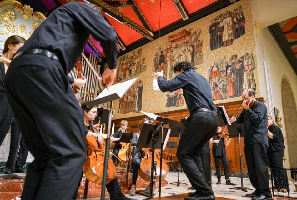 People dressed in black playing instruments in a concert hall
