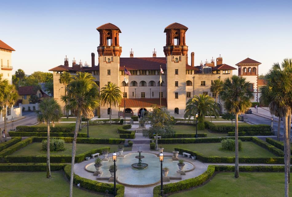 Large museum with beautiful green grass and cut hedges with a water fountain in the middle