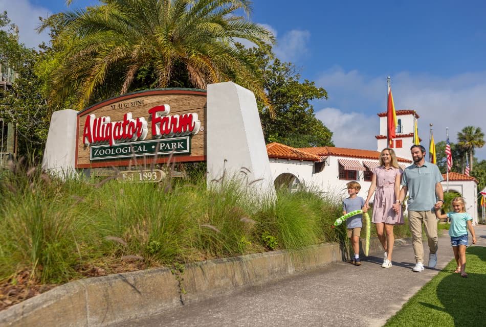 Family walking on a sidewalk next to a sign for an Alligator Farm
