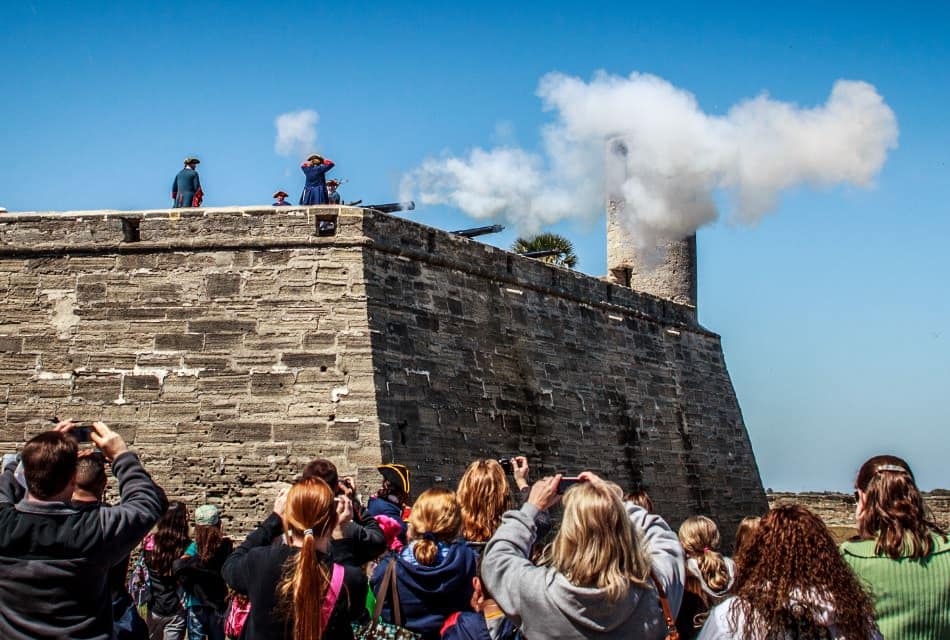 Reenactment at an old fort with canons blasting while people watch