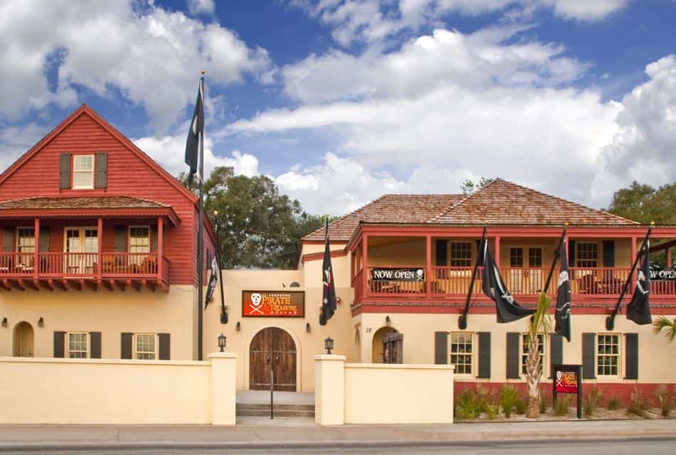 Large building painted cream with dark shutters and red painted balconies and a sign that states Pirate Treasure