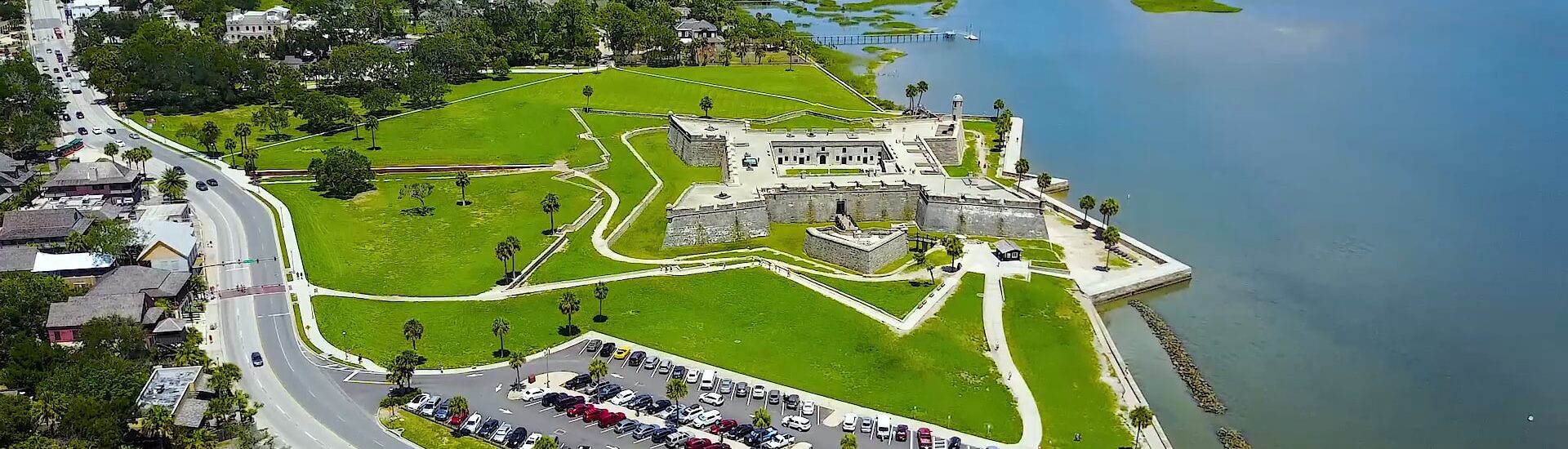 Aerial view of old fort surrounded by green grass and large body of water