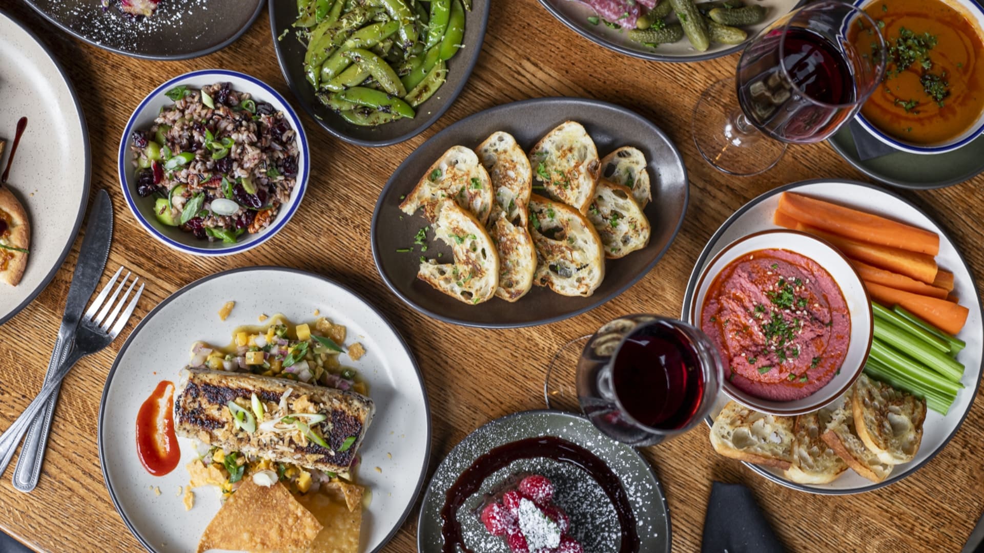 Close up view of multiple restaurant dishes on top of a wooden table