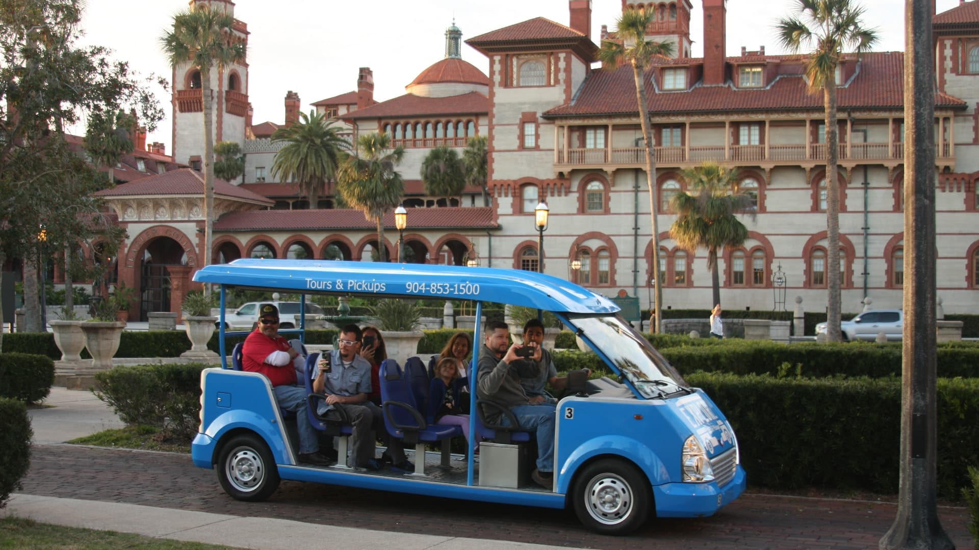 Tourists riding in small blue open shuttle