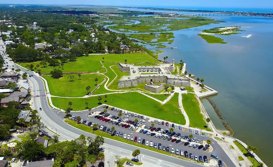 Aerial view of old fort surrounded by green grass and large body of water