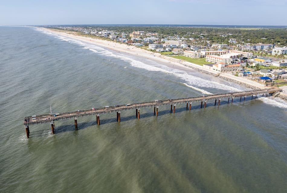 Aerial view of a large pier in the water next to a coastal town