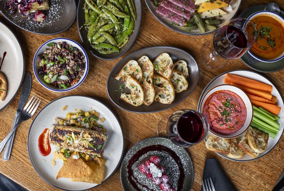 Close up view of multiple restaurant dishes on top of a wooden table