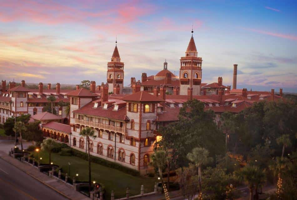 Aerial view of a college painted cream with terracotta roof and accents surrounded by grass, vegetation, and trees