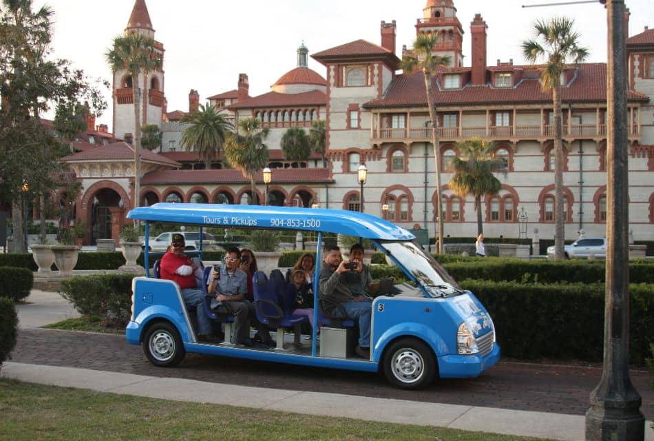 Tourists riding in small blue open shuttle